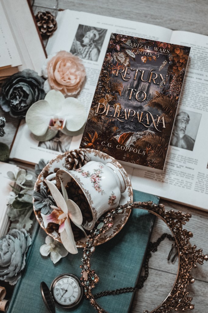 Flatlay photo of Return to Dellapalania by C.G. Coppola, styled with vintage books, a jeweled crown, a floral teacup, and orchids. The dramatic fantasy cover shows a mysterious city beyond wild ferns and golden autumn leaves under a stormy violet sky.